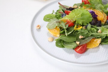 Delicious salad with tomatoes and orange slices on white table, space for text