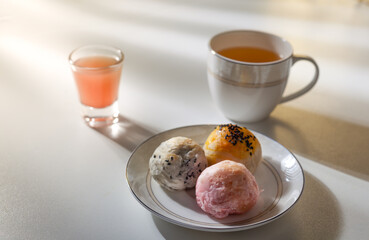 Pastries on a plate and a glass of tea on the table against the light of the morning window.