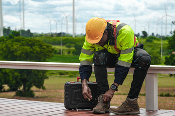 African Engineers man wearing safety shoes before walking on construction site. WIND TURBINE with...