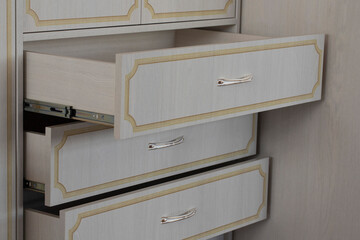 Open cabinet drawers in white with vintage yellow frames on the fronts in a retro style. New wardrobe with gilded handles and chrome rails close-up. Photo printing drawing on furniture facades.
