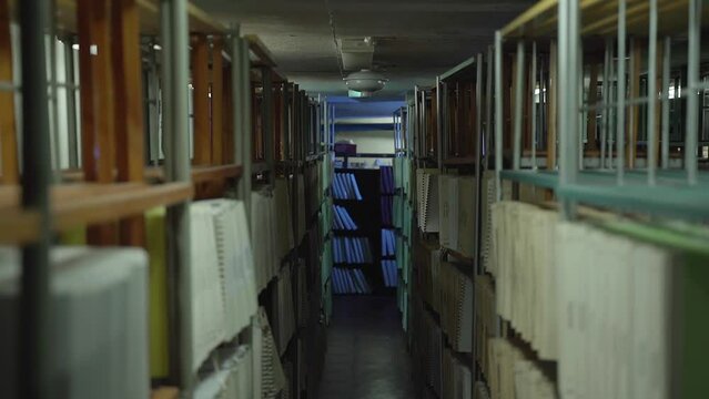 Shelves with old books in the archive. Camera movement between stylages with lighting turned on at this point