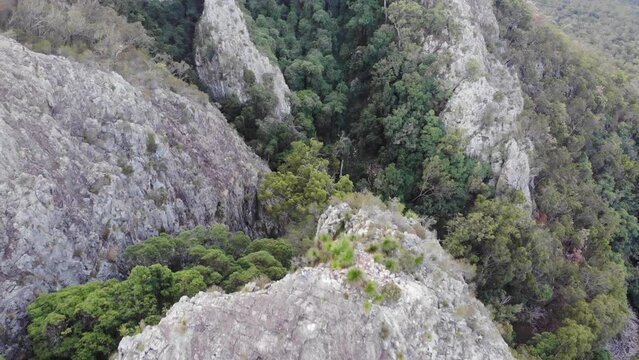 aerial view of brave hiker girl standing on a razorback ridge at the top of mount greville admiring the panorama of lake maroon; moogerah peaks national park near brisbane, queensland, australia