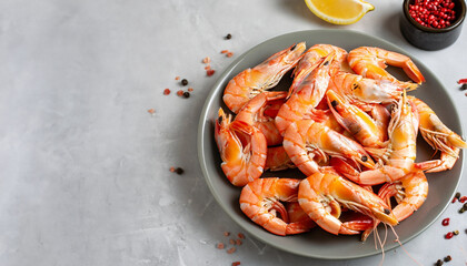 Boiled shrimps in a round plate and spices on a light gray background. Copy space