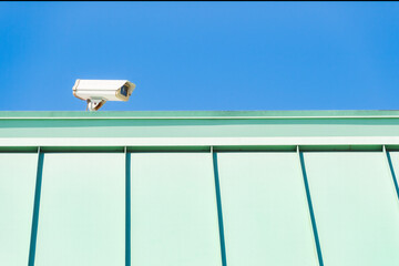 Security Camera on Left Side of Green Roof in Bright Sunlight