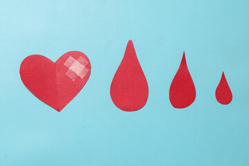 Paper heart and blood drop symbol on blue background. Hemophilia Day and World Blood Donor Day. 