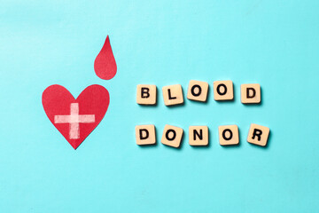 Blood donor lettering and a handmade red heart with a cross sign  for world blood donor day on blue...