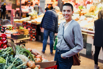 hispanic young woman with skinhead or short hair shopping vegetables on traditional market or grocery 