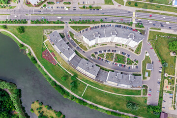 apartment buildings on riverbank and driveway with car traffic. summer cityscape. aerial top view.