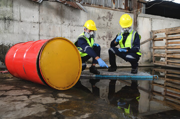 Two Officers of Environmental Engineering Wearing Protective Equipment with Gas Masks Inspected Oil Spill Contamination in Warehouse Old, Hazardous Fuel Leakage and Environmental Concept.