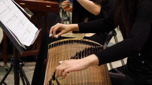 a female player playing traditional  instruments Chinese zither or guzheng.