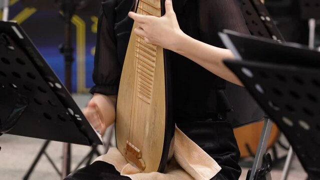 a female player playing traditional instruments Chinese lute or Pipa.
