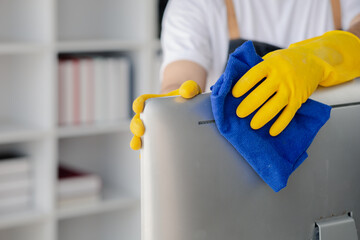 Person cleaning room, cleaning worker is using cloth to wipe computer screen in company office room. Cleaning staff. Concept of cleanliness in the organization.