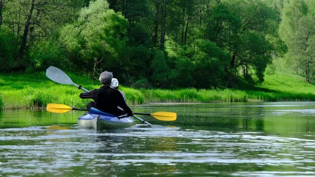 Family kayak trip for seigneur and senora. An elderly married couple rowing a boat on the river, a water hike, a summer adventure. Age-related sports, mental youth and health, tourism, active old age