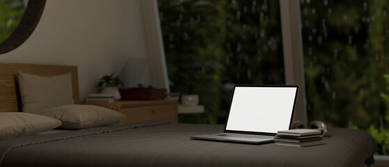 Close-up image of a laptop on a bed in a bedroom on a rainy night. Home workspace concept.