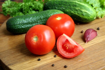 Tomatoes lie on a wooden cutting board.	