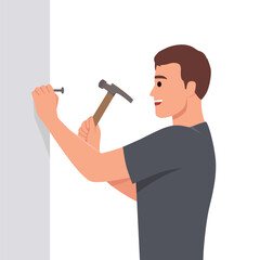 Man with hammer makes repairs in house by hammering nail into wall to hang picture. Young guy is doing repairs to improve interior of apartment or install new shelf to accommodate personal items.