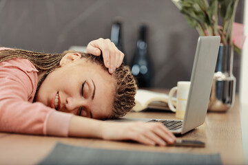 Box-braided woman asleep on laptop, tired from work