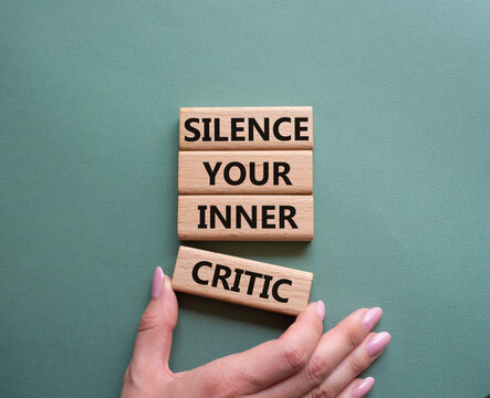 Silence your inner critic symbol. Wooden blocks with words Silence your inner critic. Beautiful grey green background. Businessman hand. Business and Silence your inner critic concept. Copy space.
