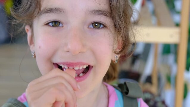 The child shakes the front baby tooth and smiles a toothless smile close-up. Changing teeth to molars in childhood