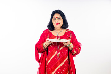 Indian woman holding pooja thali in hand on white background.