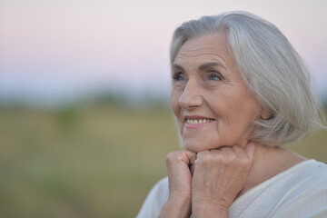 Close up portrait of happy elderly woman posing against blue sky