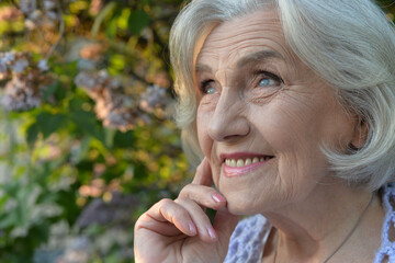 Close-up portrait of happy senior beautiful woman on background in spring park
