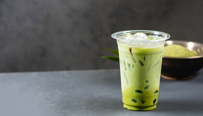 Take away glass of iced matcha green tea latte with bubble on dark gray background, copy space