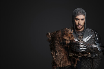 King wearing chainmail with reinforced steel plates, one shoulder covered by a fur pelt, strikes a...