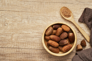 top view flat lay overhead nutmeg whole muscat nut in wood bowl on wooden table background. nutmeg whole muscat nut. pile of nutmeg whole muscat nut food background
