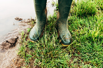 Farmer in rubber boots standing in the field after severe rain storm on flooded plantation
