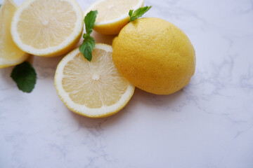 Fresh lemons and green mint composition on white marble background. Fresh tropical fruits. Slice lemon fruits.