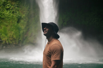Young man standing in front of a waterfall