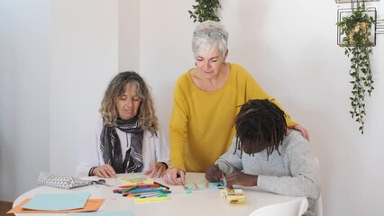 Middle-aged lesbian couple enjoying making Christmas cards with their son at home. - Powered by Adobe