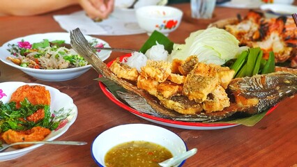 Fried fish served with seafood sauce and fresh vegetable.