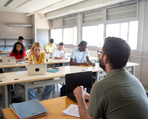 Male teacher explaining the lesson to a class of multi-ethnic students in a high school