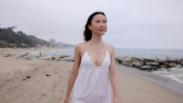 Attractive Asian woman running on the beach in Santa Monica California. Slow Motion.