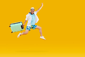 Fototapeta na wymiar Happy excited man in summer clothes, holding suitcase, hurrying to board plane, running fast, and jumping high in air isolated on orange yellow background. Holiday trip, vacation, travel, rush concept