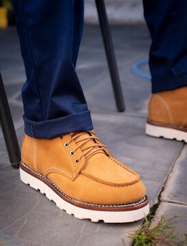 Men fashion in leather boots, Close up view on man's legs in blue jeans and yellow leather boots.