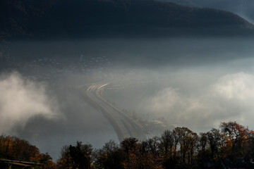 Mountain View over a Highway on Lake Lugano with Cloudscape with Sunlight on Clear Sky in Lugano,...
