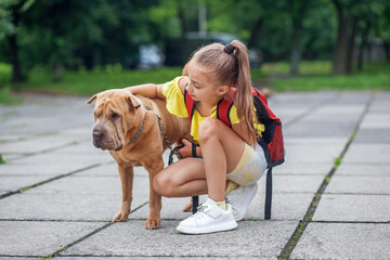 Child walking with dog. School girl after school having fun dog outdoors. Pets concept