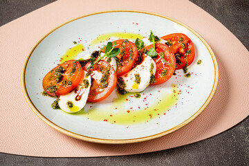 Tomato and mozzarella with basil leaves on plate