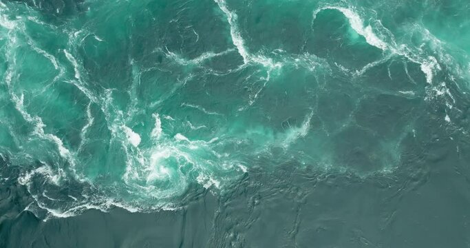 Azure blue swirls and vortex in Saltstraumen tidal maelstrom; drone top down