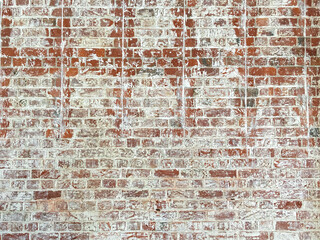 Distressed red brick wall with remnants of white paint that had peeled off over an extended period...