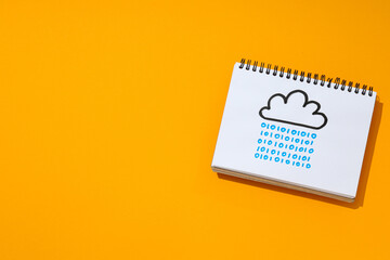 Notebook with a drawn cloud on an orange background, cloud computing concept, place for text