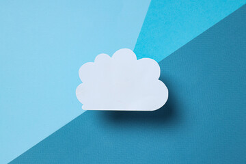 A white, paper cloud on a gray background, top view