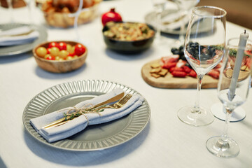 Knife, fork and green spicy herb on folded napkin tied up together with thread lying on grey plate on table served with homemade food