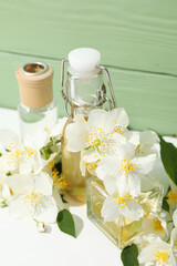 Fototapeta na wymiar Jasmine flowers and perfume bottles on green wooden background