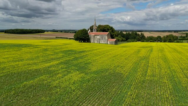 Aerial view French Countryside, Yellow rapeseed field panorama with wind turbine or wind wheels, Sainte-Radegonde Chapel, Courant, Charente Maritime, France, High quality 4k footage