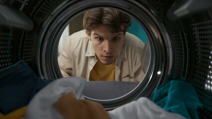 View from inside the washing machine, adult man looking inside the washer drum