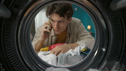 View from inside the washing machine, young man takes out the dirty clothe and talking on smartphone